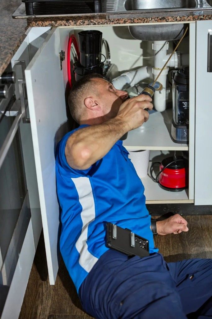 Sydney technician treating under kitchen sink for cockroaches